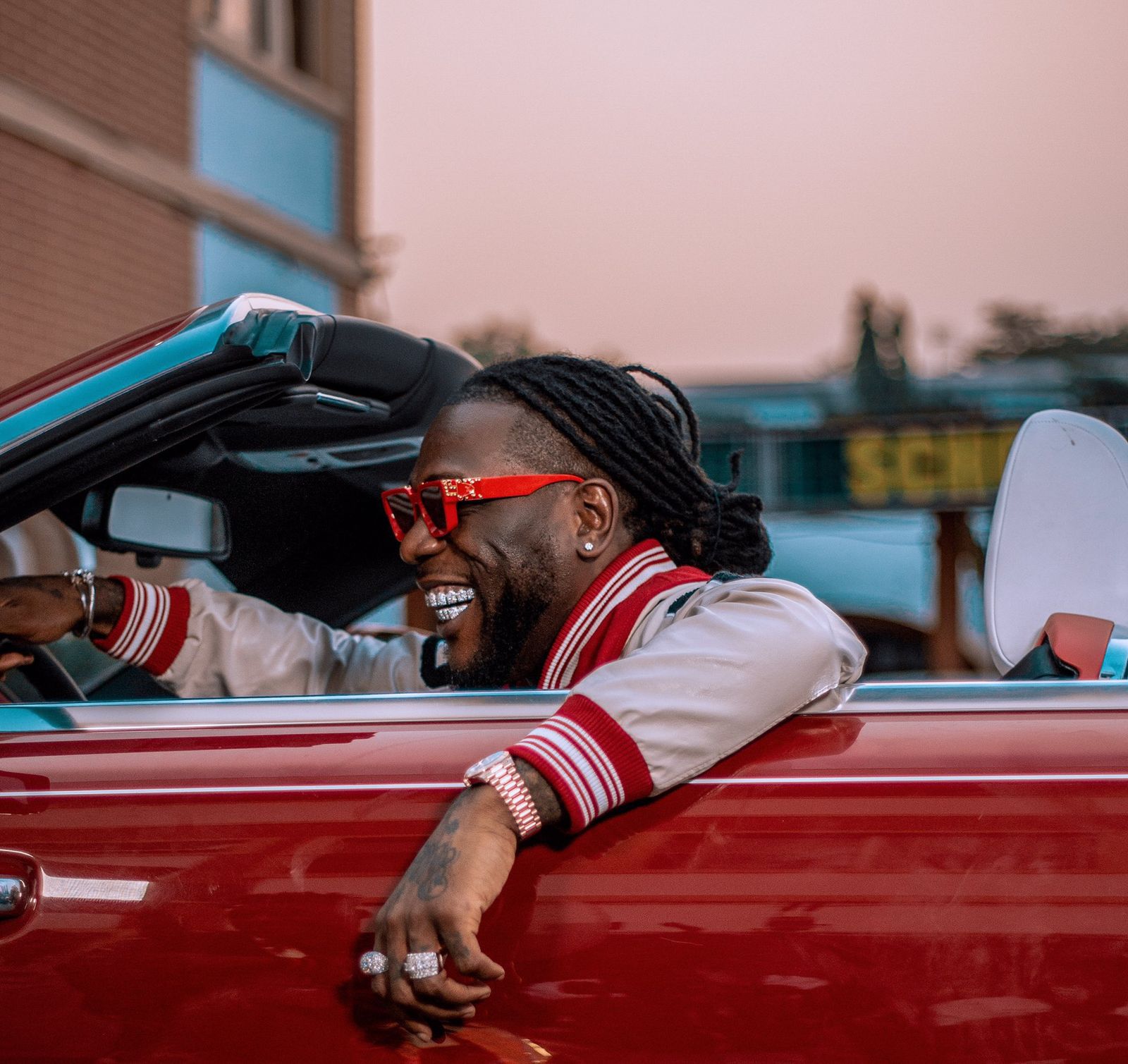 Burna Boy in a Red Rolls Royce Car Wearing Red Sunglasses